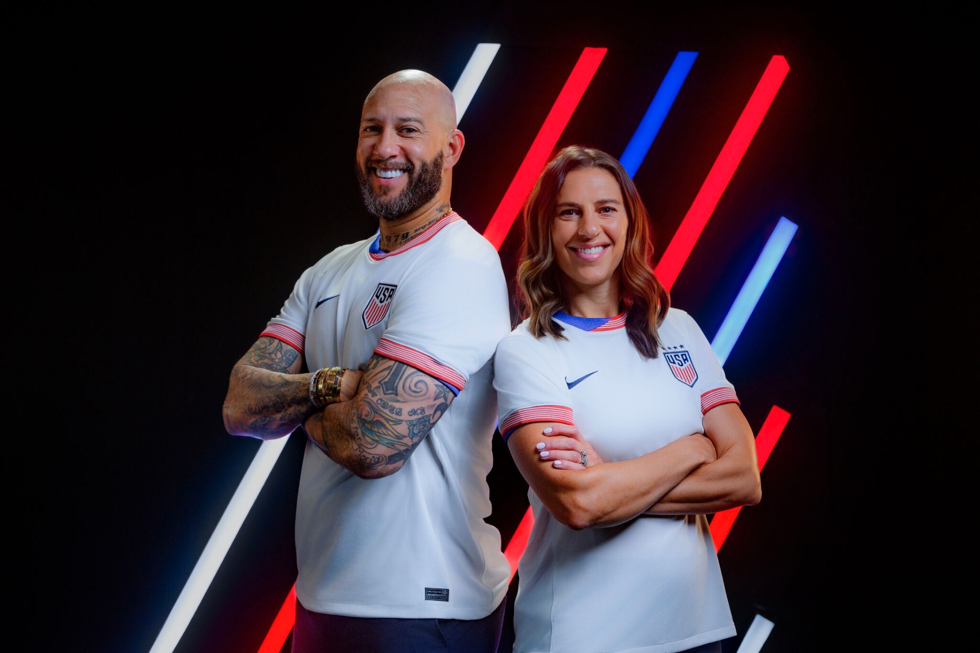 Two U.S. Soccer athletes in team kits under neon lighting